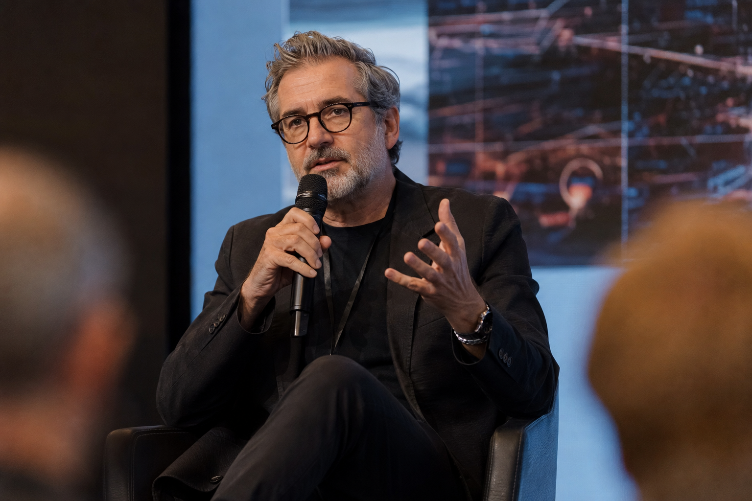 Speaker with microphone addressing an audience at a film and AI industry panel
